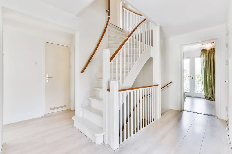 Escalier tournant blanc et bois dans une entrée lumineuse